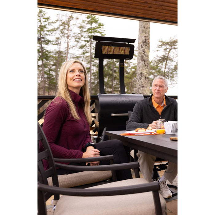 Two people sitting at a table outdoors with a Tungsten Portable Heater in the background