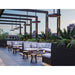 Modern outdoor patio with sectional sofa, chairs, and decorative elements such as the Bromic Eclipse Heaters hanging from pillars, against a cityscape