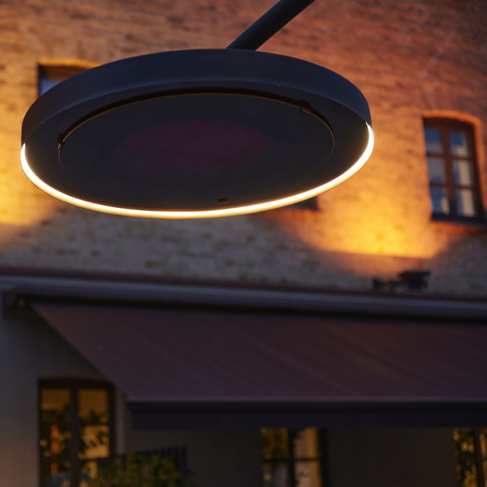 Close up photo of the head of the Bromic Smart Heat Eclipse Portable heater's head in a low light settings with brick building in the background