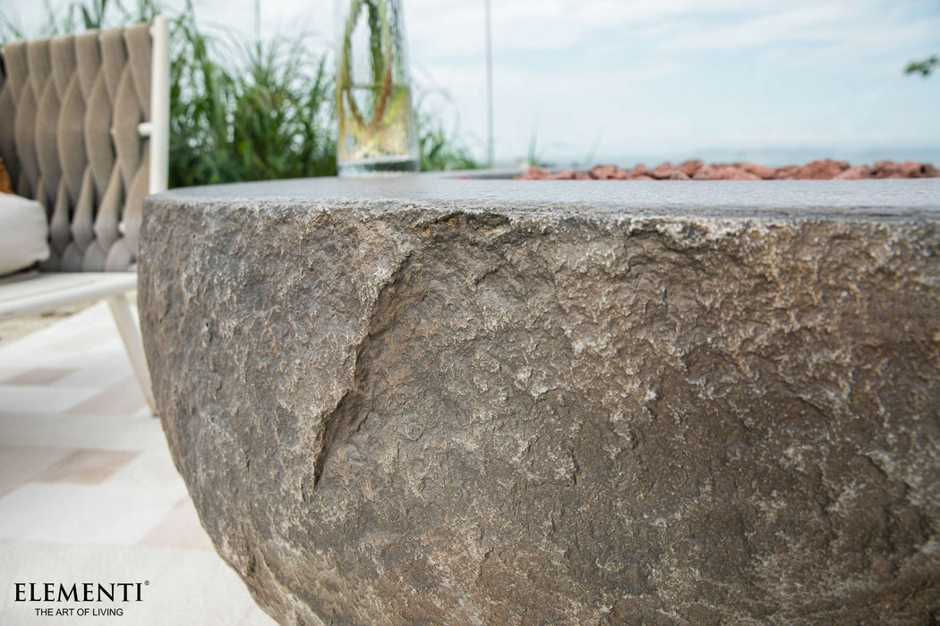 Close-up of a stone fire pit with 'Elementi' branding in an outdoor setting.