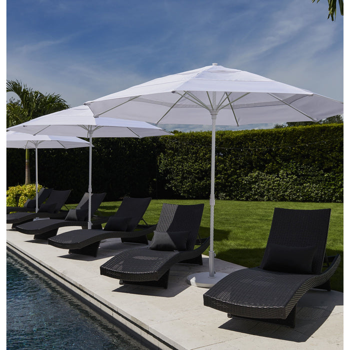 Black lounge chairs under white umbrellas by a pool with a hedge and sky background