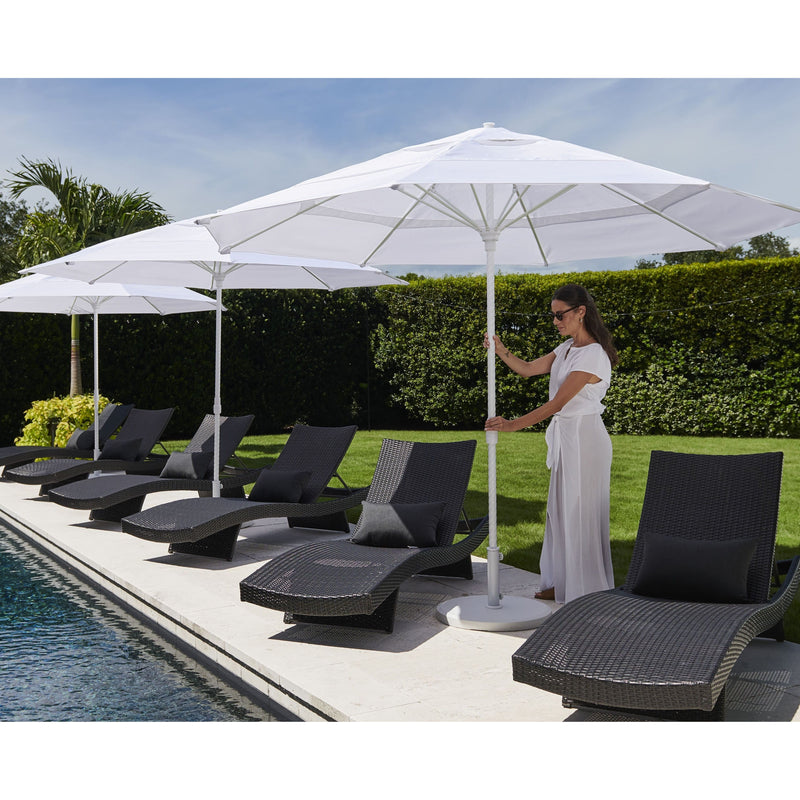 Woman adjusting a large white Helux market umbrella near lounge chairs by a pool