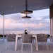 Outdoor dining area with a table and chairs under Bromic Eclipse Heaters used as a modern pendant light, set against a twilight sky.