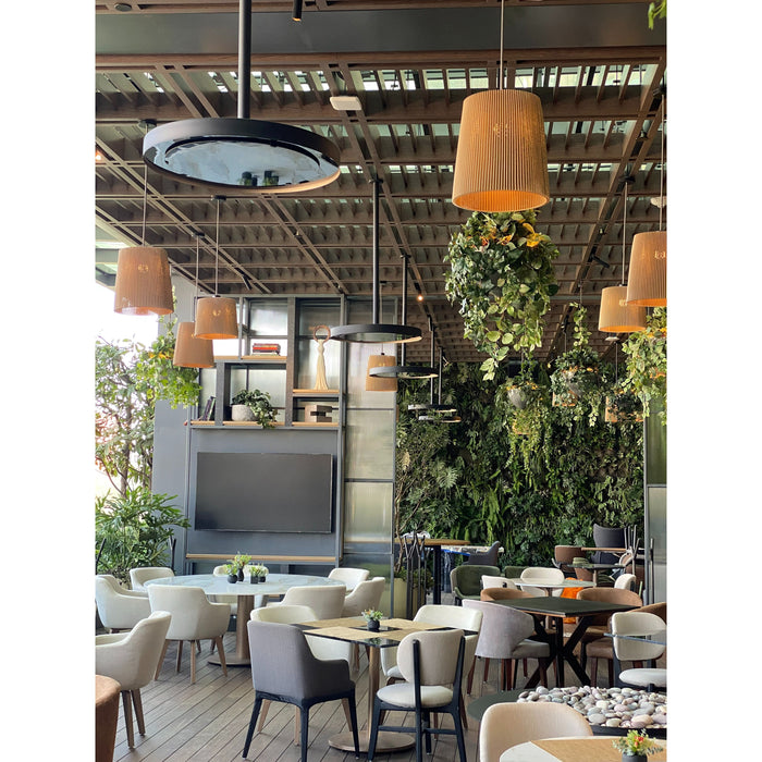 Modern restaurant interior with tables, chairs, and hanging Bromic Eclipse Heaters that are also being used as lights.