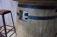 Elementi Lafite Wooden barrel table with a black strap and a stool in the background