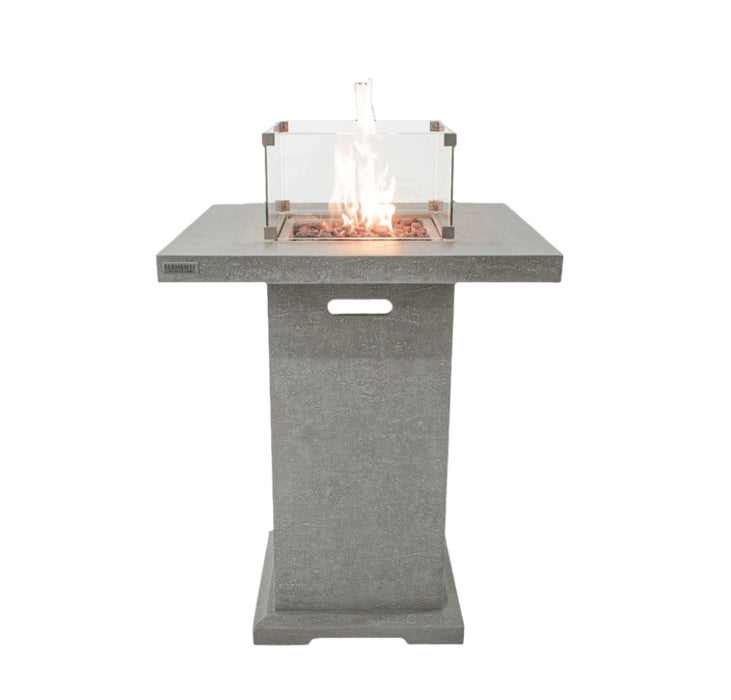 Concrete Elementi Montreal fire table that has an ignited flame with glass cover on a white background