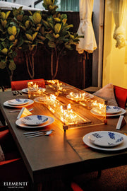 Elementi Sonoma Dining table set with plates, and decorative elements in a warm indoor setting.
