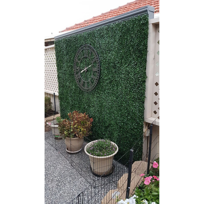 Faux Boxwood Hedge Panels Installed Along a Fence with a Large Outdoor Clock