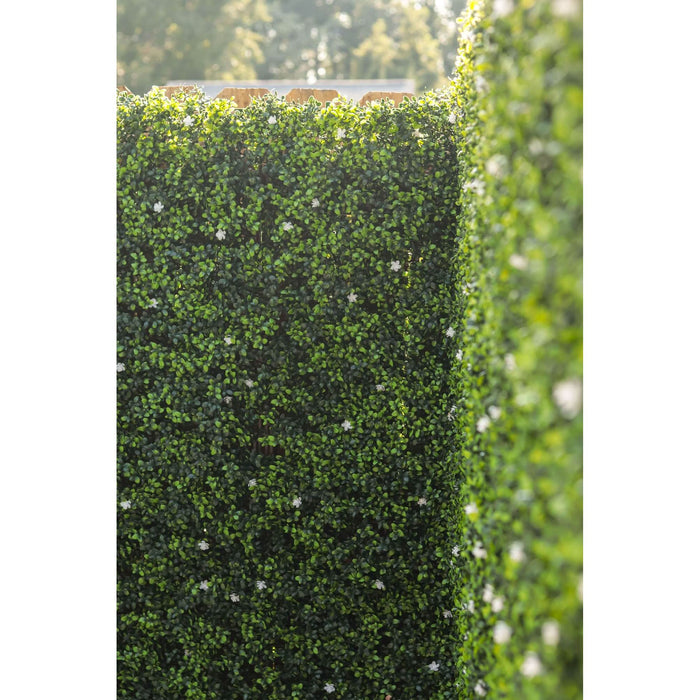 Artificial Boxwood Mat with Faux Flowers Installed Outdoors onto a Fence with White Flowers