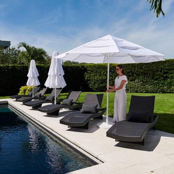 Woman standing by a poolside with lounge chairs and umbrellas