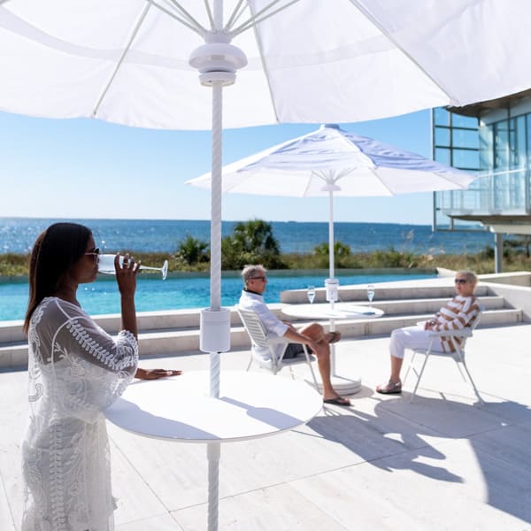 People enjoying a drink with the Helux Table on a patio with ocean view