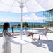 People enjoying a drink with the Helux Table on a patio with ocean view