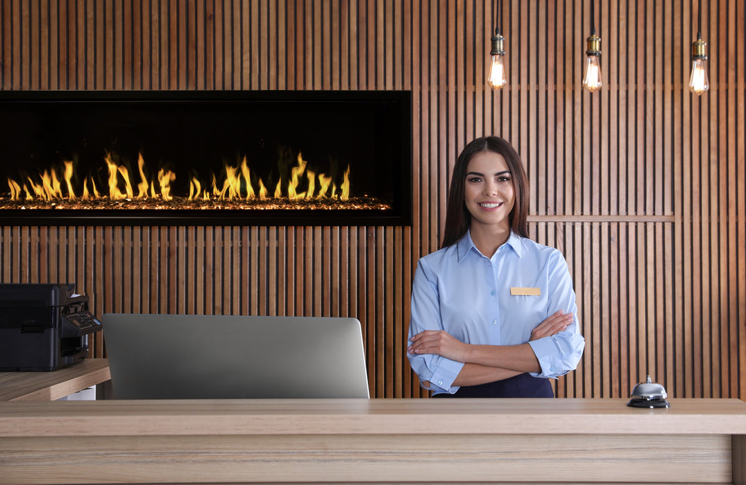 Woman standing behind a reception desk with an Orion Slim fireplace in the background