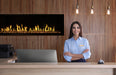 Woman standing behind a reception desk with an Orion Slim fireplace in the background