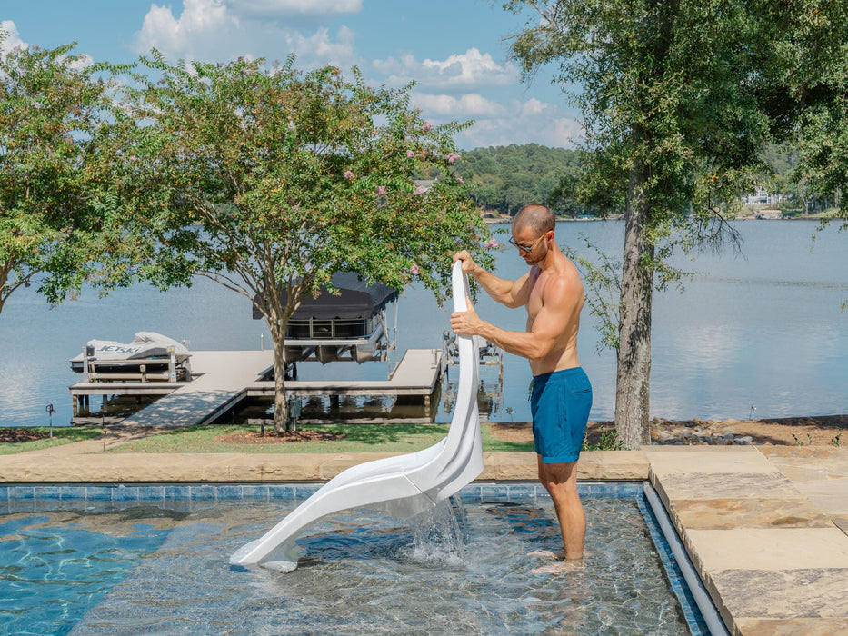 Man lifting a white TenJam Laylo Lounger out of a pool to empty the water of out it
