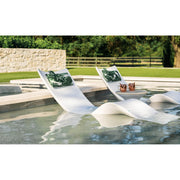Two white lounge chairs with green headrest pillows by a poolside.