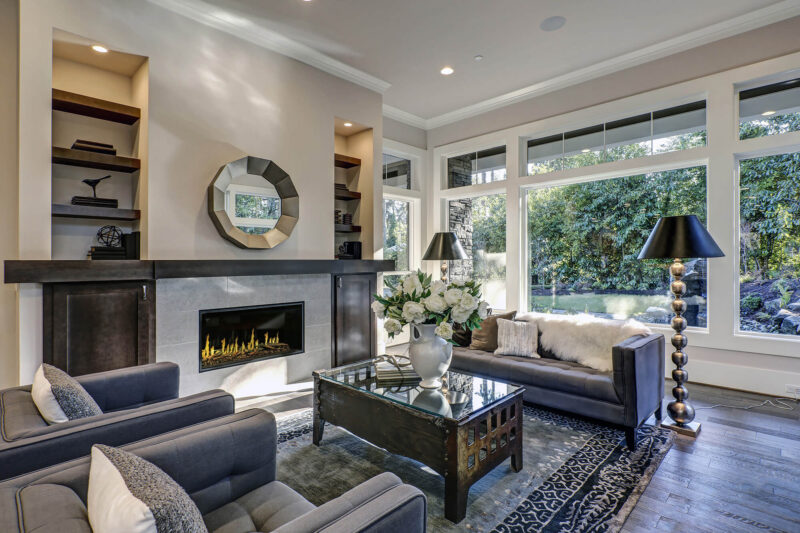 Modern living room with gray sofas, a fireplace, and large windows.