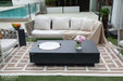 Outdoor patio setting with a sectional sofa, Elementi Metropolis Fire table, and decorative elements.
