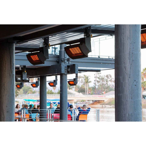 Infrared Bromic Tungsten heaters mounted on a structure with people sitting below in an outdoor setting.