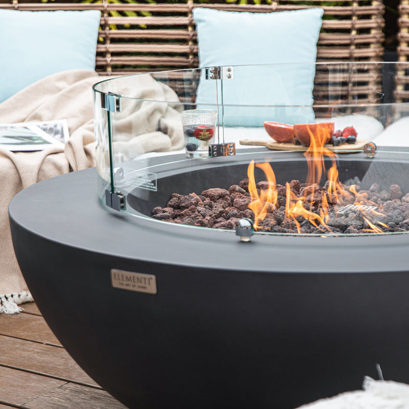Close up image of Elementi Lunar fire pit bowl table with flames and a cozy outdoor setting.