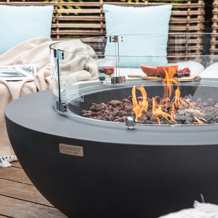 Close up image of Elementi Lunar fire pit bowl table with flames and a cozy outdoor setting.