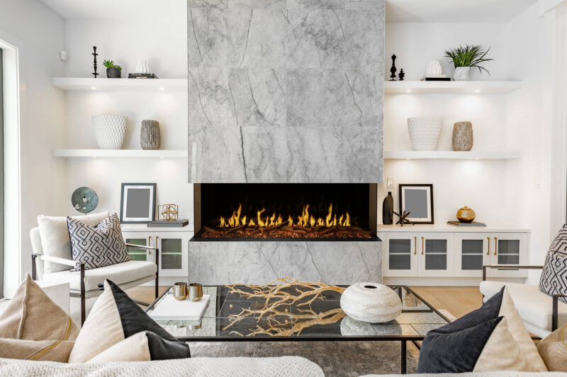 Modern living room with a marble fireplace and white shelves.
