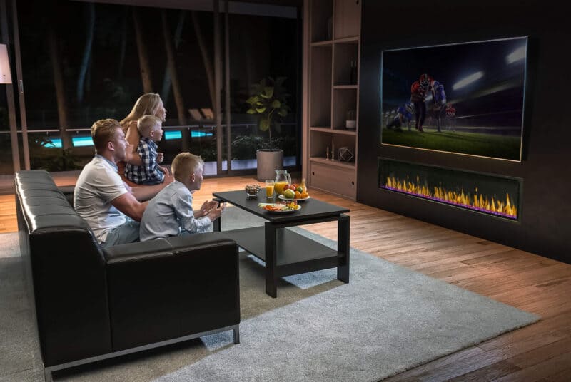 Family watching TV in a modern living room with a virtual fireplace beneath the tv