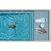 Birdseye view of two people relaxing in a pool with two Shayz lounge chairs on the tanning ledge and a TenJam side table in between the chairs. 