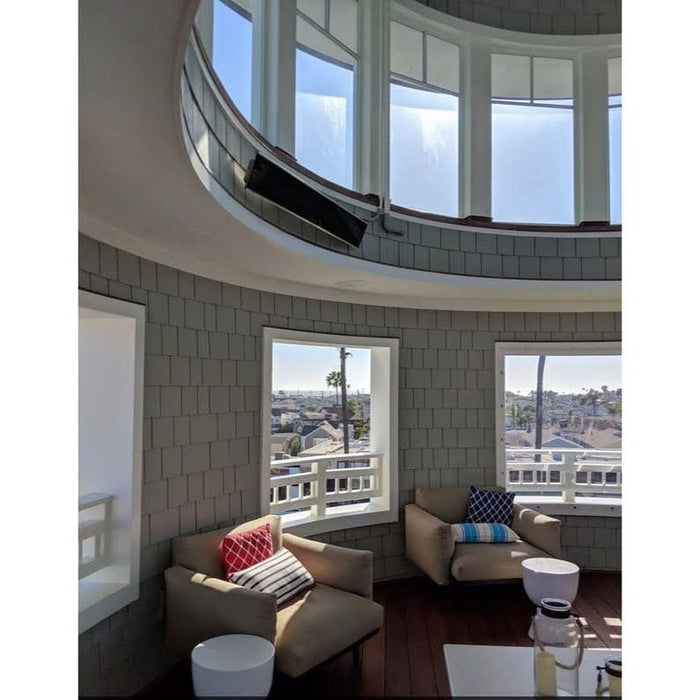 Modern living room with circular window design, a Bromic Platinum Electric Heater wall mounted above, and cityscape view