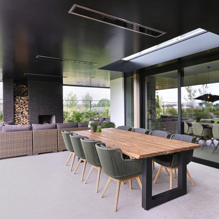 Modern outdoor dining area with a wooden table and chairs in a stylish home setting and recessed black Platinum Heaters by Bromic