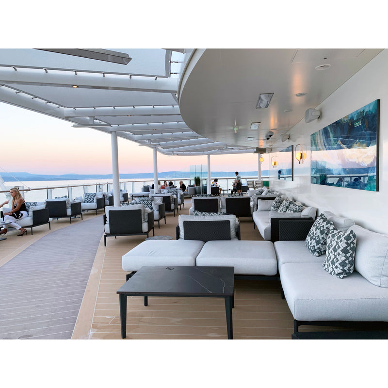 Outdoor lounge area with white sofas, black tables, and ocean view.