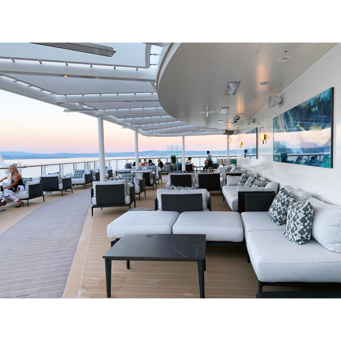 Outdoor lounge area with white sofas, black tables, and ocean view.