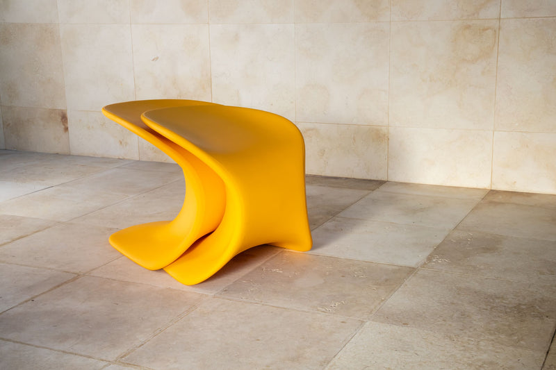 Two TenJam Drift chairs stacked on top of one another on a tiled floor with a beige wall background