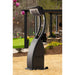 Outdoor black freestanding patio heater in a garden setting with a house and trees in the background