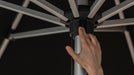 Hand adjusting a patio umbrella on a black background