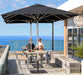Two people sitting under a large black umbrella by Shadowspec on a rooftop with ocean view
