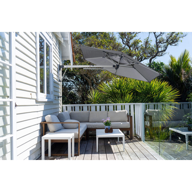 Shadowspec Retreat Wall Mounted Umbrella at a tilted angle providing shade over a patio sectional.
