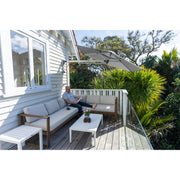 Man sitting on patio reading a book under the shade provided by the Shadowspec Retreat wall mounted umbrella