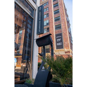 Starbucks Reserve Roastery sign on a building exterior with outdoor seating area with a freestanding square head patio heater in the forefront