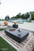 Outdoor patio with Elementi Metropolis Fire table, chairs, and pool in the background