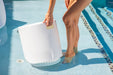 Woman using the handle on the side of the TenJam ripple side table to lift it out of her pool