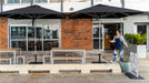 Person standing near outdoor tables and Shadowspec Oasis umbrellas in front of a building with a 'Open' sign.