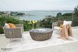 Outdoor patio set with chairs, table, and cushions overlooking a scenic view.