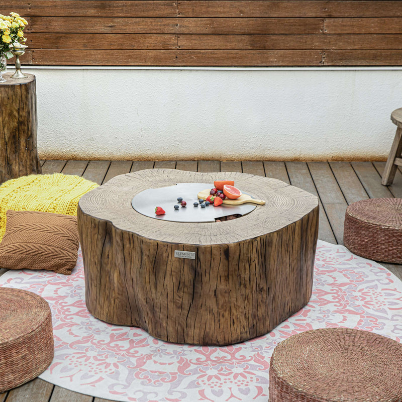 Outdoor setting with a wooden fire pit table, ottomans, and decorative elements on a wooden deck.