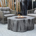 Outdoor patio setting with wicker chairs and a Elementi Manchester fire pit table.