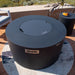 Round Elementi Pacaya outdoor fire pit with lid on a patio