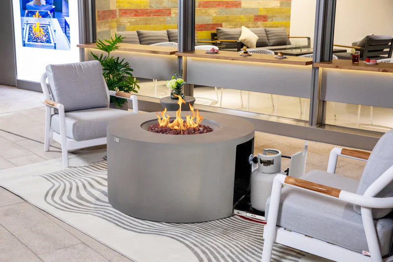 Modern outdoor patio with fire pit, chairs, and a colorful wall in the background