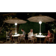 People sitting at outdoor tables with illuminated LED patio umbrellas at night.
