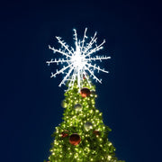 Decorated Christmas tree with a large snowflake light on a dark blue sky background