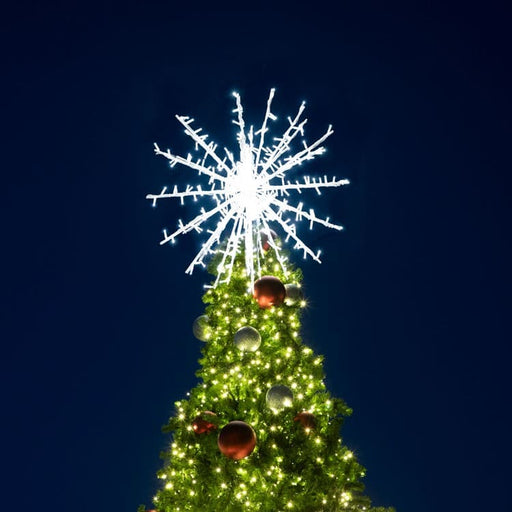 Decorated Christmas tree with a large snowflake light on a dark blue sky background